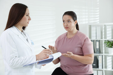 Nutritionist with clipboard giving recommendations to overweight woman in hospital