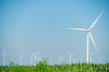 Wind turbines generate clean energy in a rural landscape with green fields under a clear blue sky