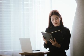 A young woman is relaxing in a cozy coffee shop, smiling as she sips her coffee. She uses her...