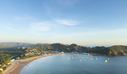 Coastal view of serene bay with boats and lush hills in afternoon light