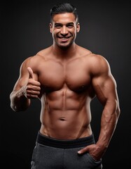 Fototapeta premium Muscular Man Shows Thumbs Up Smiling Against Dark Background