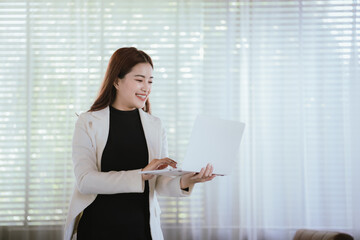 Smiling Thai Asian businesswoman working in a modern office. She is overflowing with...