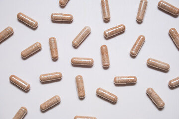 Capsules of dietary supplement are scattered on beige background.