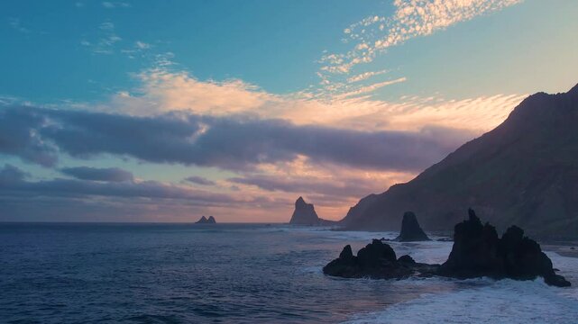 Ocean waves crash on rocks and spray in beautiful sunset light near Playa de Benijo beach in Tenerife, Canary Islands