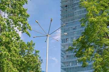 Lanterns on the mast for lighting streets in the city. A lamp post is visible among the greenery of...