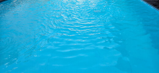 Top view of water surface in swimming pool. Ripples on surface of water in pool. Liquid flows from reservoir into a swimming pool. Surface of water with waves background. Blue reflective water

