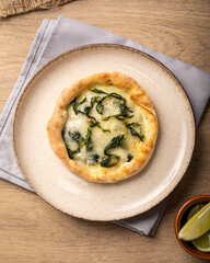 esfiha de escarola com mussarela em um prato sob uma mesa de madeira 