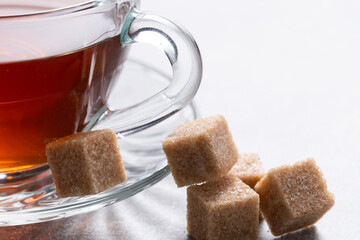 Cup of tea with brown sugar cubes on a white background.