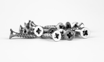 A collection of metal screws scattered on a white background