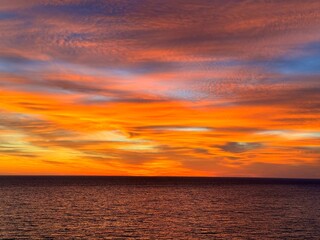 Bright sunset sky over calm dark ocean
