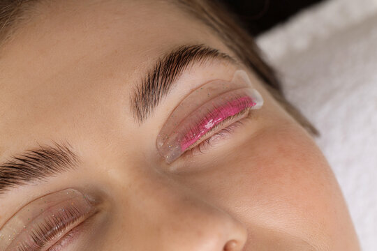 Woman undergoing eyelash laminating procedure in beauty salon, closeup