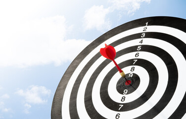 dart on target board with blue sky background