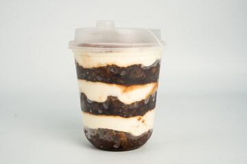 Tiramisu in a clear plastic cup showing the layers isolated on white background
