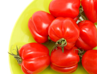 Small bright red deeply ribbed tomatoes isolated on white background
