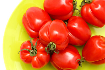 Small bright red deeply ribbed tomatoes isolated on white background