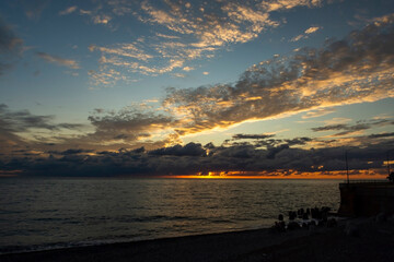 Red sunset over the sea, rich in dark clouds, rays of light. Black Sea coast, early autumn