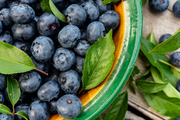Blueberries lie on a wooden surface in a plate. Blueberries scattered on a wooden table