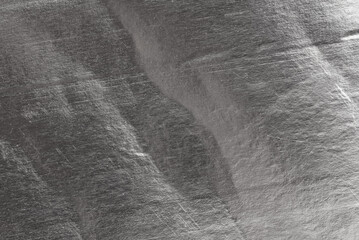 Texture of crumpled silver foil. Foil with dents, folds and wrinkles
