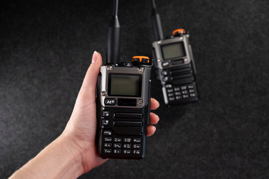 Two professional handheld radios with sleek black designs and antennas placed on a dark textured surface. Compact and durable, these devices are ideal for communication in outdoor or tactical settings