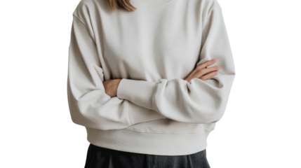 A close-up view of a young woman in a casual beige sweater, standing with arms crossed, exuding confidence and comfort in a relaxed setting.