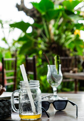 Outdoor Cafe Table and focus to Empty Glasses and Sunglasses in a Tropical Setting