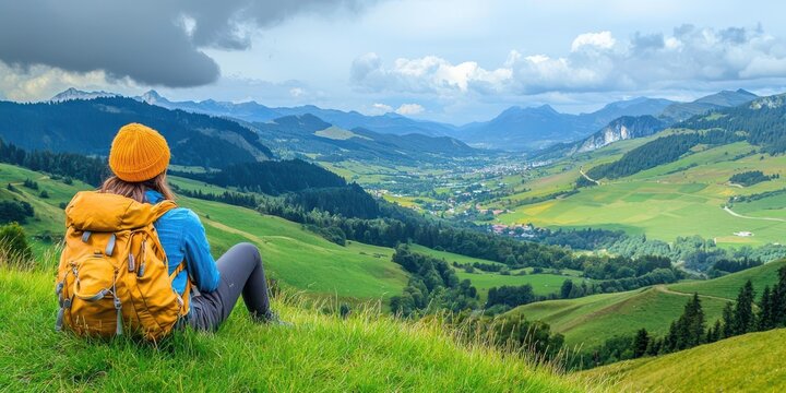 A hiker resting on a grassy knoll overlooking a tranquil valley
