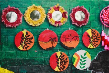 Colorful woven art displayed on a vibrant green wall in a lively marketplace