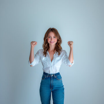 mujer atractiva con los pu&ntilde;os en alto con vaqueros y camisa blanca