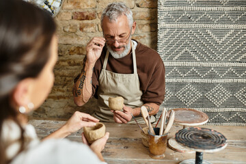 A beautiful couple enjoys quality time in a pottery class, shaping clay and sharing smiles.