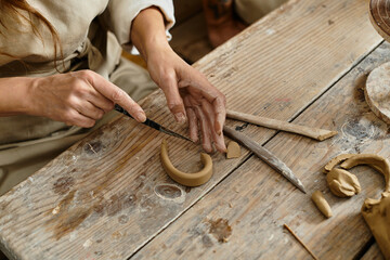 cropped woman enjoys a pottery class, shaping clay