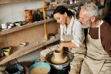 A couple shapes clay together in a pottery class, sharing joyful moments and love.