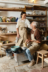 A beautiful mature couple enjoys shaping clay in a pottery class, sharing quality time together.