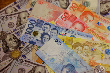 Collection of Philippine currency bills and coins displayed on a wooden surface