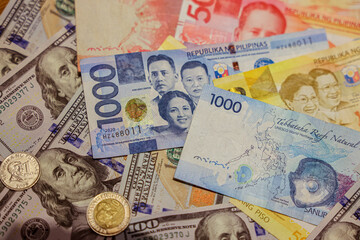 Currency collection featuring Philippine pesos and US dollars on a wooden surface