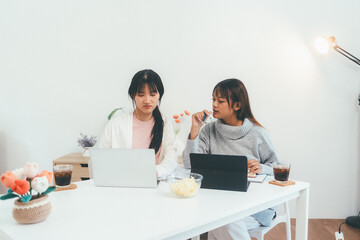 Female higher education student using laptop and studying book in home, Online learning.