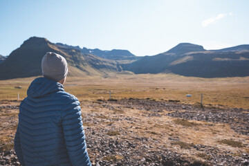 Fototapeta premium Man with a wanderlust spirit observes the majestic volcanic mountains of the Snafellsnes Peninsula in western Iceland. The scene reflects serenity and natural beauty