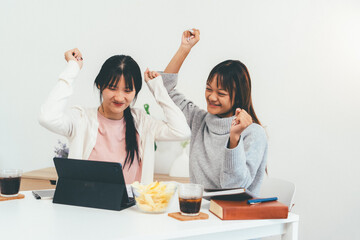 Female higher education student using laptop and studying book in home, Online learning.