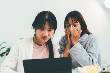 Female higher education student using laptop and studying book in home, Online learning.