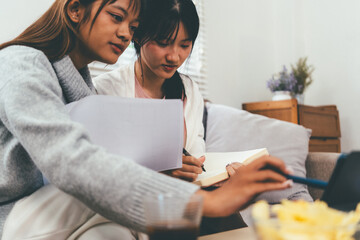 Female higher education student using laptop and studying book in home, Online learning.