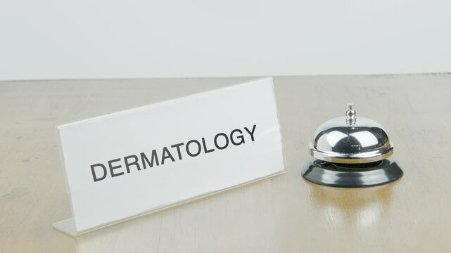 Dermatology Office or Room with Hand Ringing The Bell on Desk or Table Multiple Times