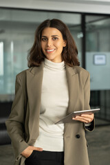 Vertical portrait of 30s beautiful successful hispanic young business woman with tablet pc smiling...