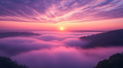 A breathtaking pink sunrise illuminates a misty valley creating a dreamlike, ethereal landscape with layers of clouds and mountains
