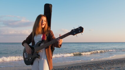 Girl Walks And Plays The Bass Instrument On The Beach Near The Ocean At Sunset