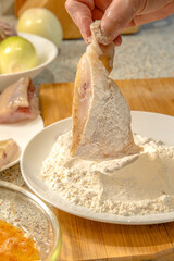 Chef dips pieces of fresh fish in flour before further frying in a frying pan
