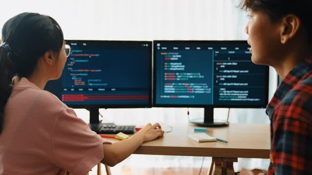Slow motion back end software developer engineer for computer programming working together on debugging writing computing code, solving complex algorithms display on monitor in office. Burgeoning