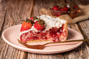 torta de morango com creme de chantilly e morangos frescos sob um prato de ceramica em uma mesa de madeira e morangos em um potinho atrás 