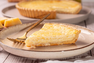 Quiche de queijo com elementos ao redor da cena como pratos, queijo e azeite 