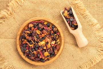 Carpathian forest tea on a wooden plate with a wooden spoon on a jute cloth, macro, top view.