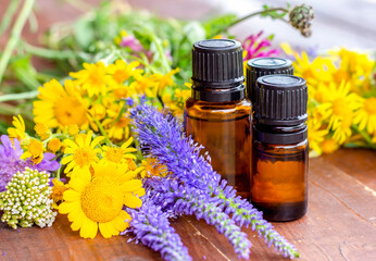 Essential oils. Dark (brown) glass bottles with essential oil and medicinal flowers, herbs on a wooden table