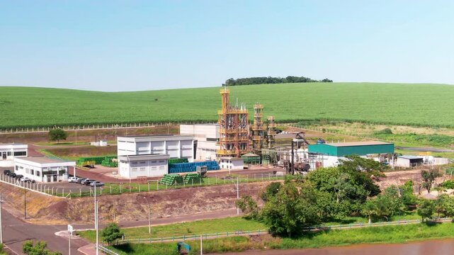 Drone shot capturing small refinery with beautiful green field at background.
